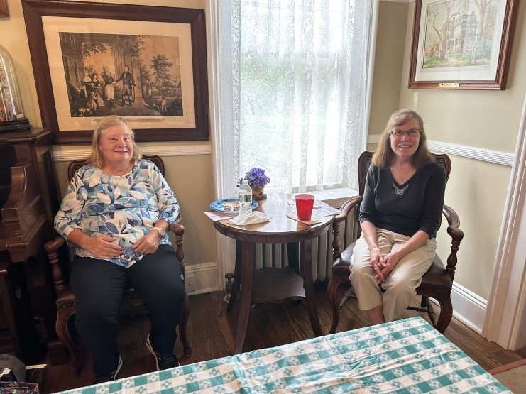 Three women seated near a fireplace during the annual picnic.