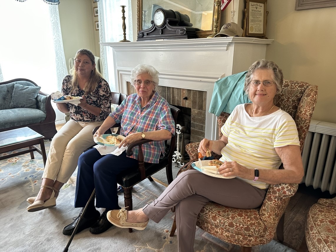 UCHS members smiling and eating during the indoor annual picnic.